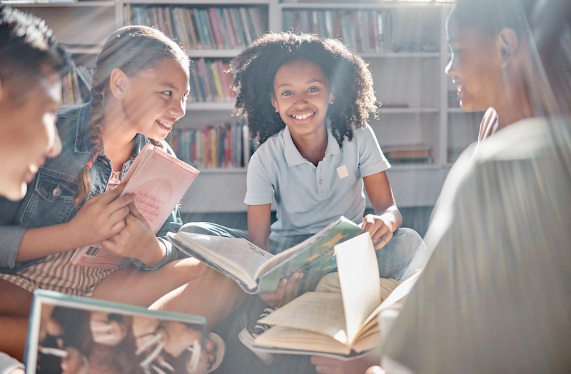 alunos em biblioteca com livros em maos conversando