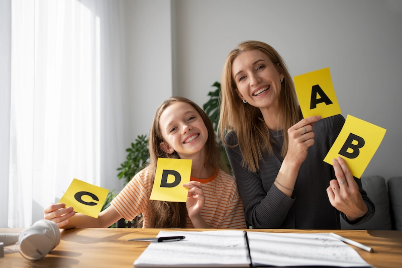 professora e aluna com flashcards de letras na aula de ingles