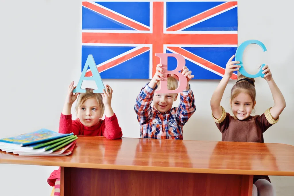 alunos segurando letras do alfabeto na aula de ingles