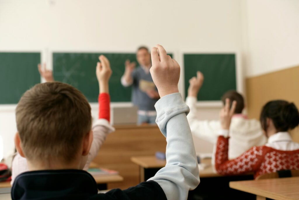 alunos levantando a mão na sala de aula foto pexels